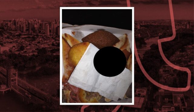 Na imagem podemos ver uma caixa cheia de salgados. Há um circulo preto tampando o pedaço do dedo encontrado