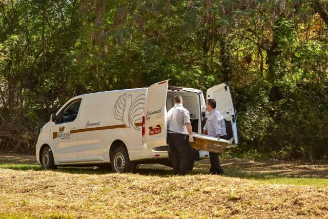 Uma foto dos agentes da funerária removendo o corpo das margens da lagoa