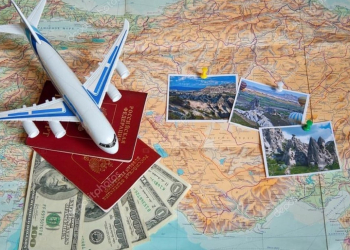 Uma foto de um avião, dinheiro e passaporte sobre um mapa mundi