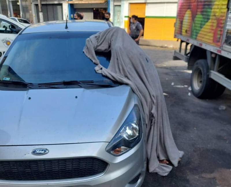 Homem morre e fica em pé, ao lado de carro; populares se assustam